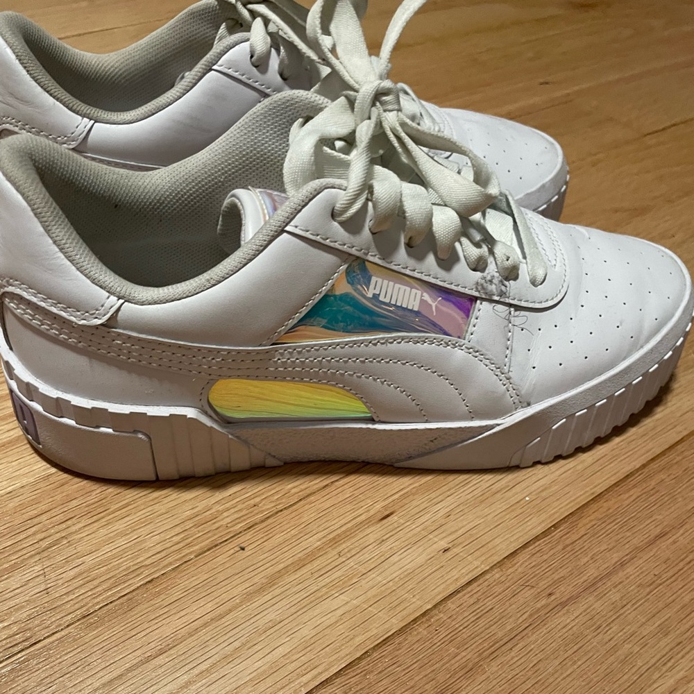 Womens white Pumas with iridescent reflective patches.